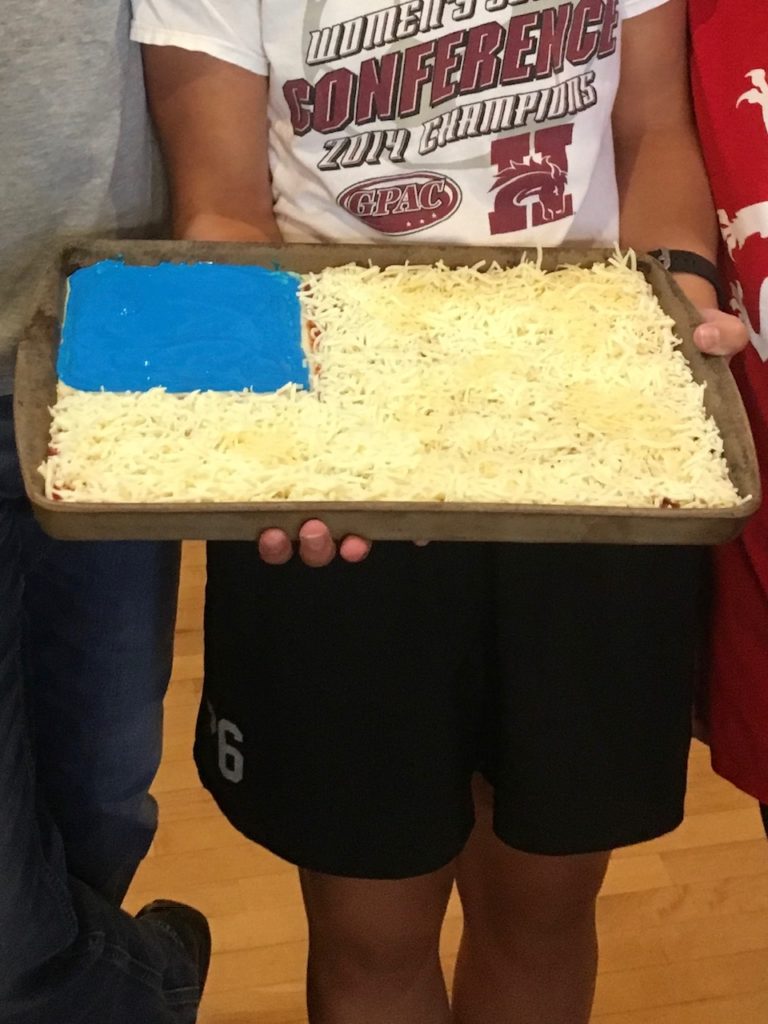 Patriotic pizza, just before it went into the oven.  Cheese on the pizza.  The blue part is food coloring with Alfredo sauce