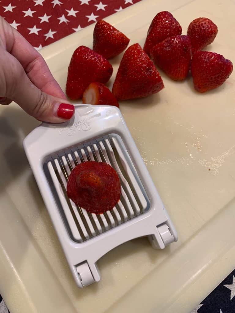 Using an egg slicer to slice strawberries for a fruit pizza