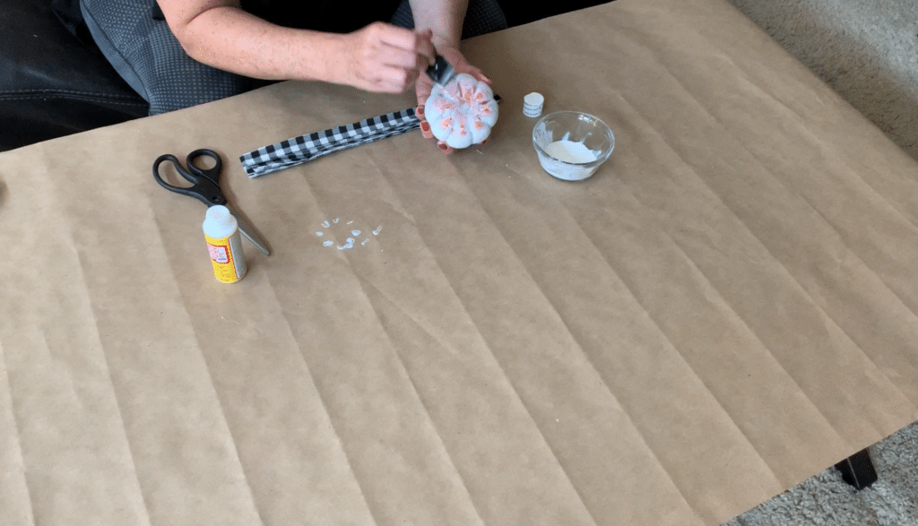 Brushing Mod Podge onto foam pumpkin