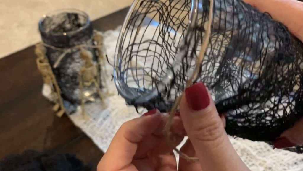Halloween Decorations DIY: Dollar Tree Skeletons tied onto black mesh covered vase with candle