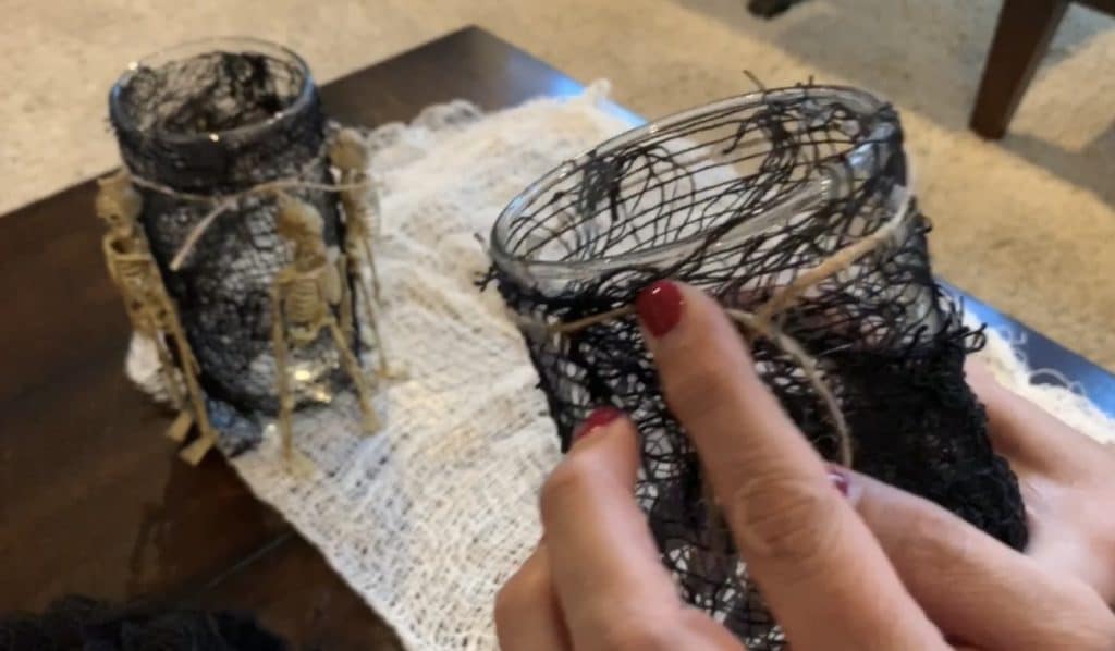 Halloween Decorations DIY: Dollar Tree Skeletons tied onto black mesh covered vase with candle
