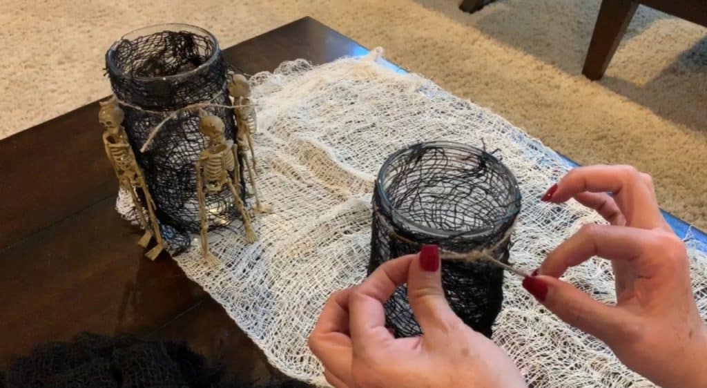 Halloween Decorations DIY: Dollar Tree Skeletons tied onto black mesh covered vase with candle