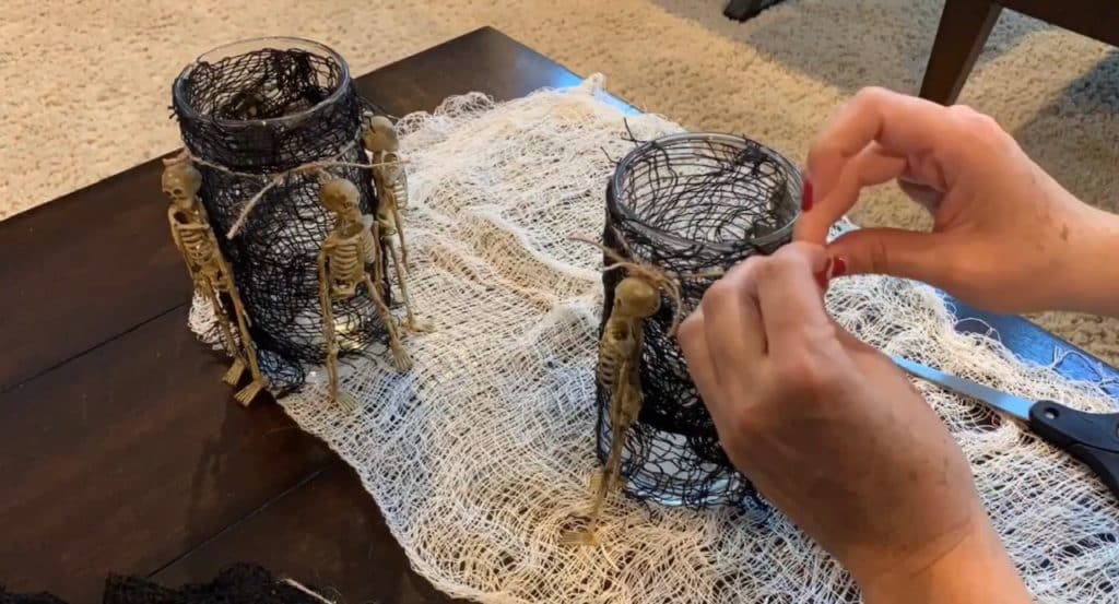 Halloween Decorations DIY: Dollar Tree Skeletons tied onto black mesh covered vase with candle
