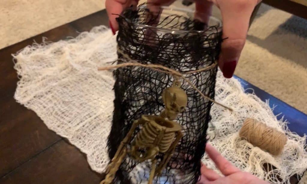 Halloween Decorations DIY: Dollar Tree Skeletons tied onto black mesh covered vase with candle