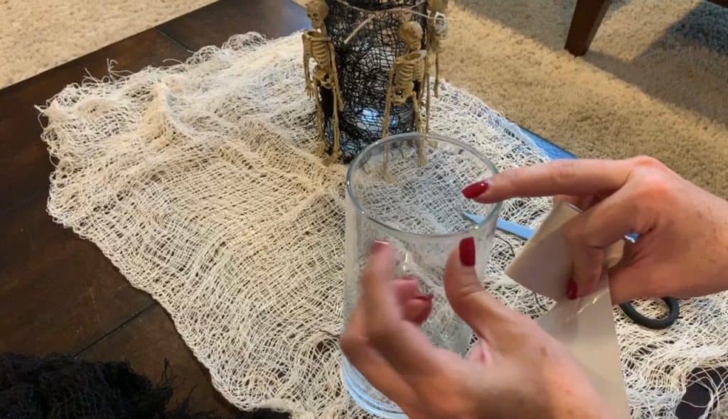 Halloween Decorations DIY: Dollar Tree Skeletons tied onto black mesh covered vase with candle