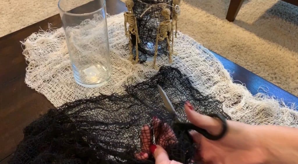 Halloween Decorations DIY: Dollar Tree Skeletons tied onto black mesh covered vase with candle