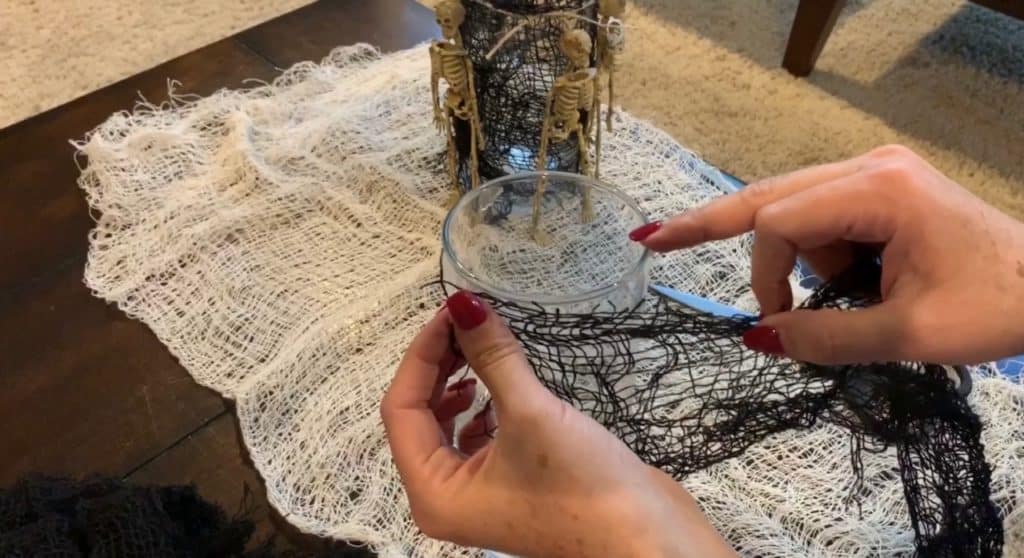 Halloween Decorations DIY: Dollar Tree Skeletons tied onto black mesh covered vase with candle