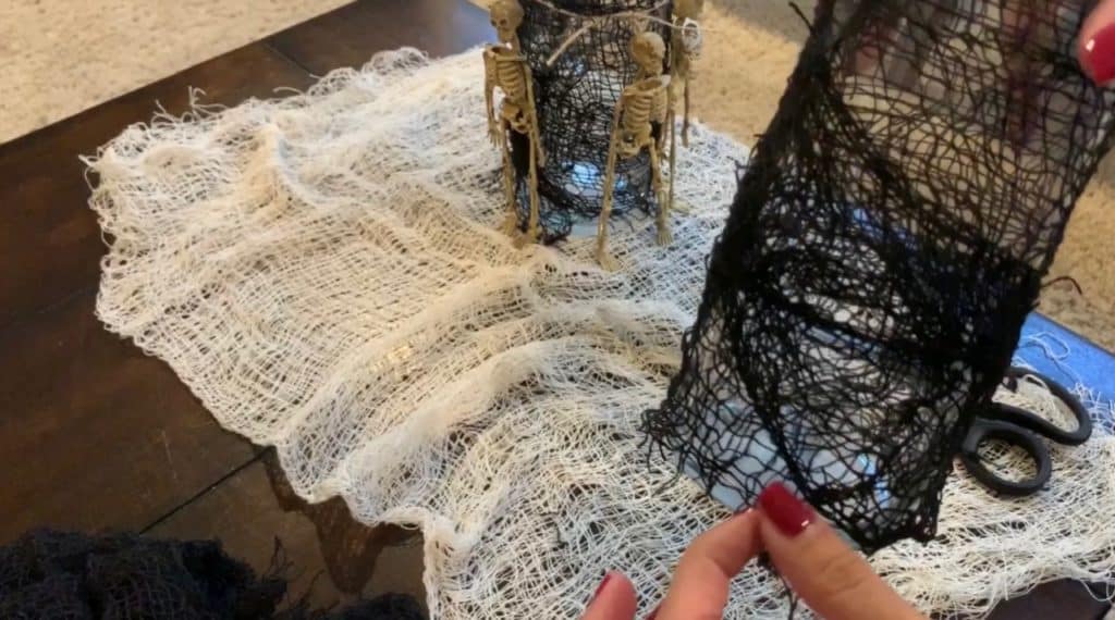 Halloween Decorations DIY: Dollar Tree Skeletons tied onto black mesh covered vase with candle