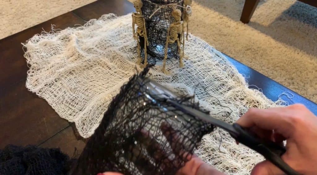 Halloween Decorations DIY: Dollar Tree Skeletons tied onto black mesh covered vase with candle