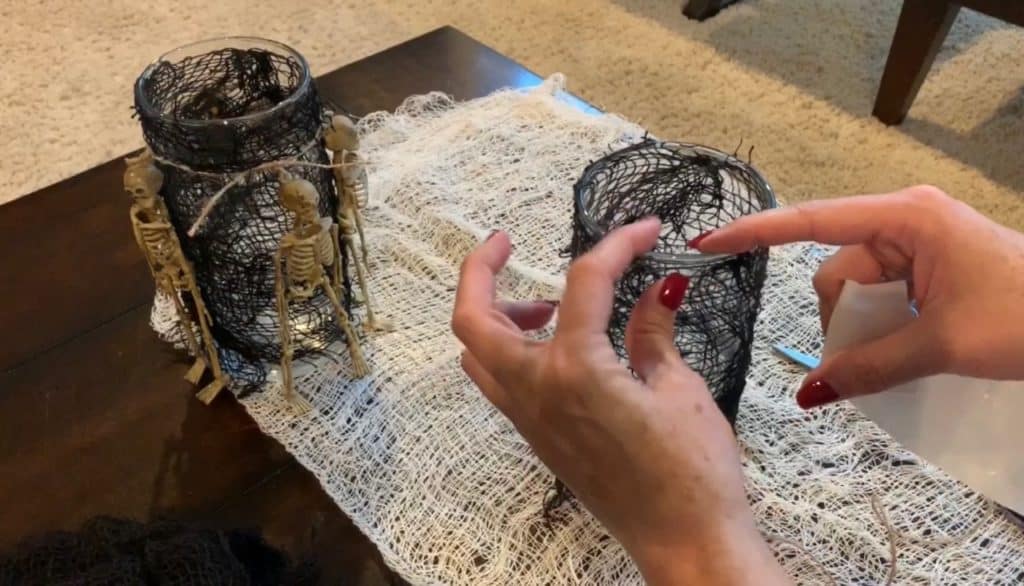 Halloween Decorations DIY: Dollar Tree Skeletons tied onto black mesh covered vase with candle
