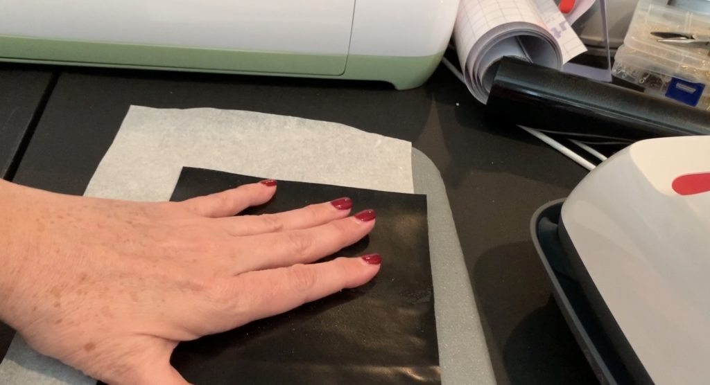 iron everyday heat transfer material onto the back of a cork sheet with a Cricut Easy Press