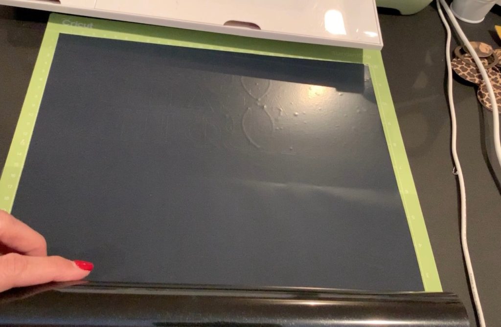 black heat transfer vinyl being cut with a Cricut machine