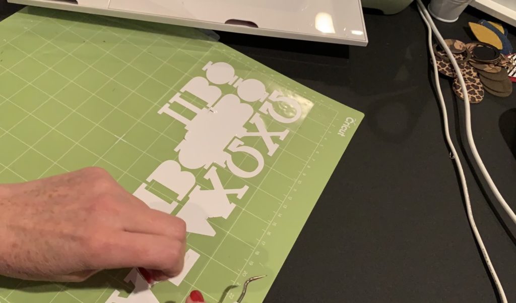 white heat transfer vinyl, cut and being weeded on a Cricut mat