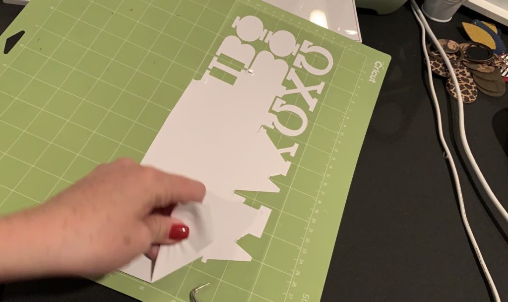 white heat transfer vinyl, cut and being weeded on a Cricut mat