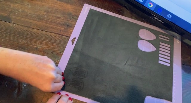 LOVE leather earrings still on the mat after being cut on Cricut