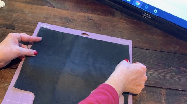 placing genuine leather on a Cricut mat to cut leather earrings on a Cricut