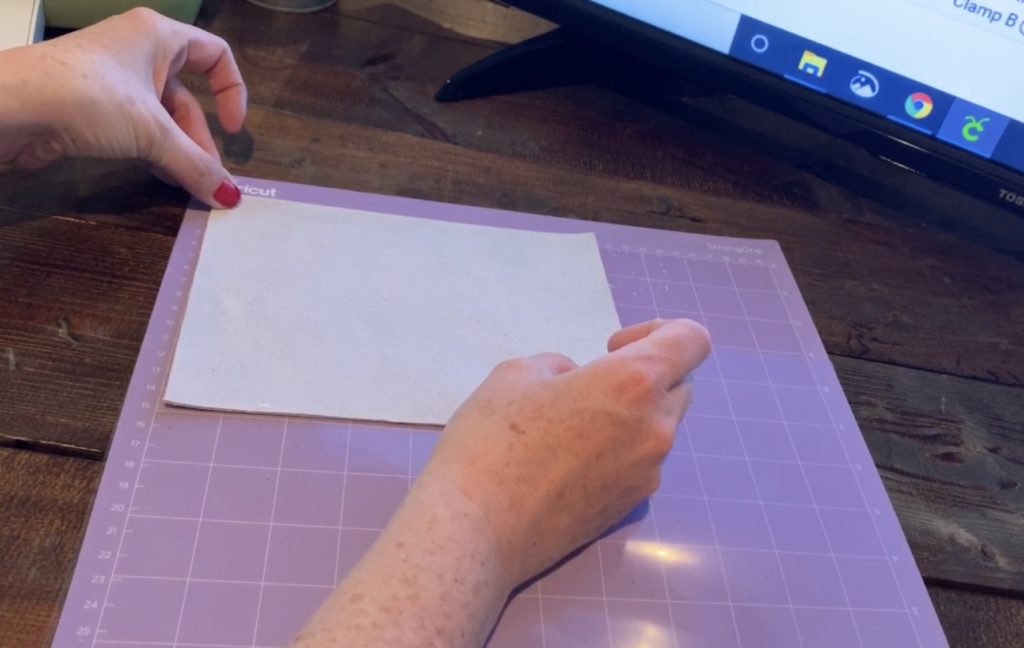 placing leather onto the Cricut mat so that the diy leather earrings could be cut