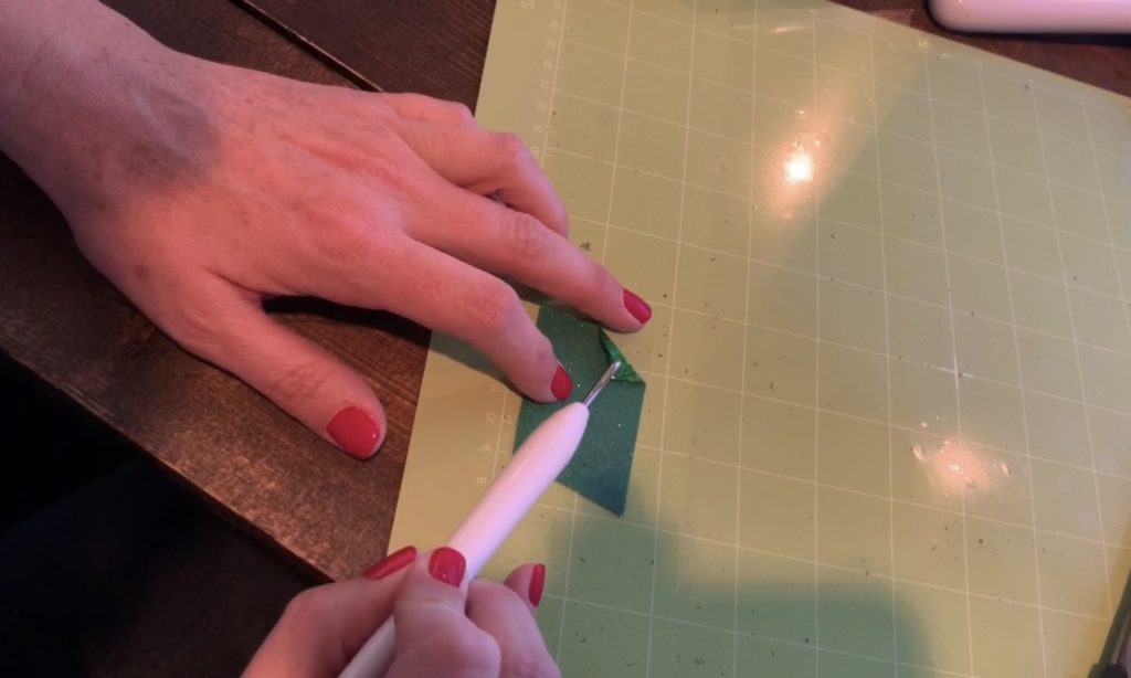 weeding green glitter heat transfer vinyl on the standard grip Cricut mat