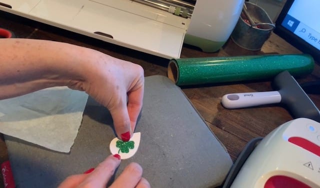 placing shamrock heat transfer vinyl onto the white teardrop leather earring