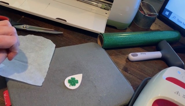 placing shamrock heat transfer vinyl onto the white teardrop leather earring