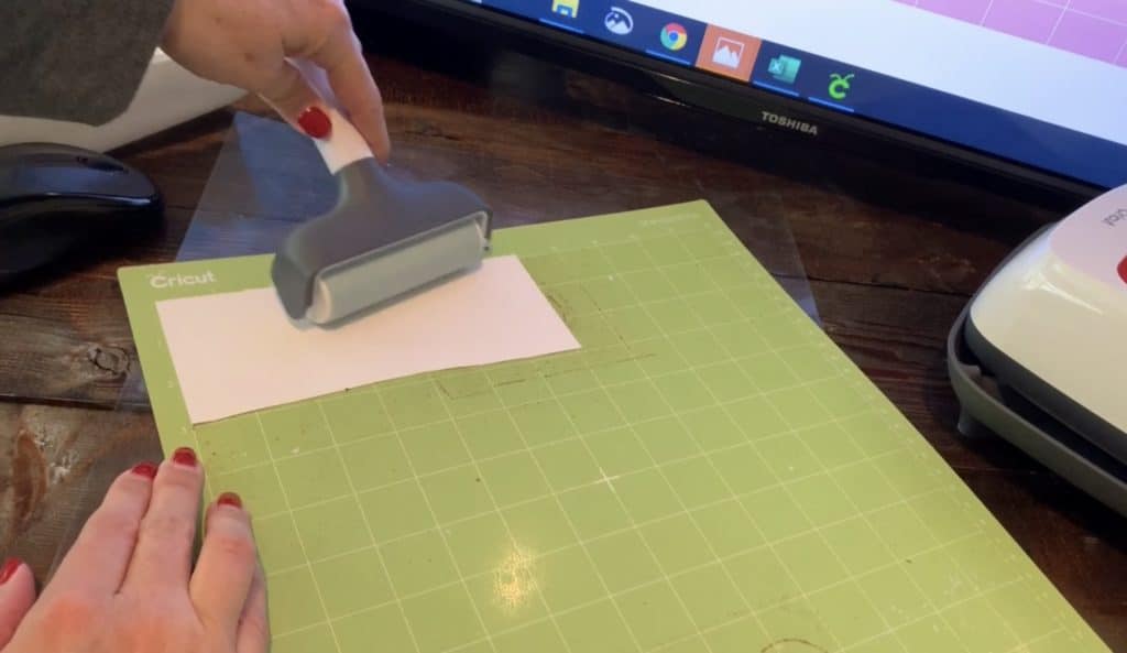 using Cricut brayer to press transfer tape onto mat