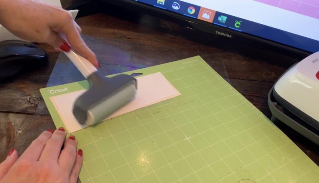 pressing faux leather onto Cricut mat with Cricut brayer