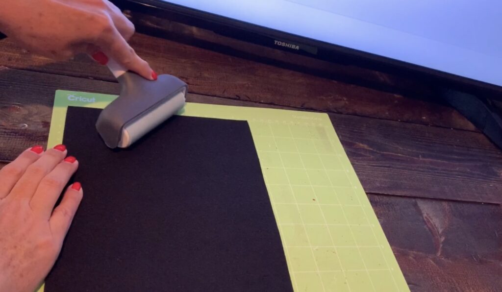 using Cricut brayer to press faux leather onto the Cricut mat