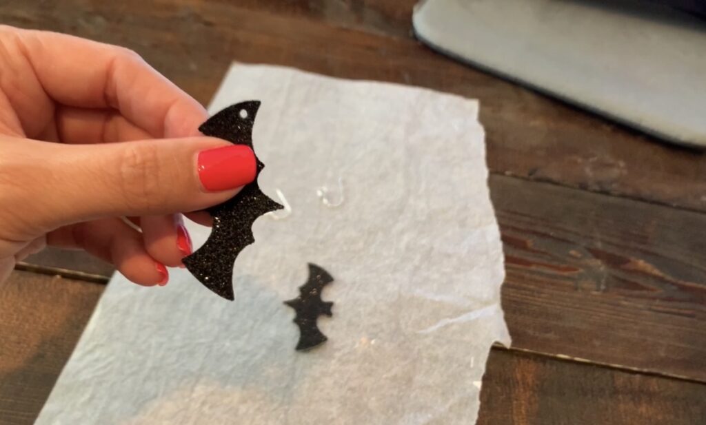 using a leather hole punch to put holes in the bat earrings diy project