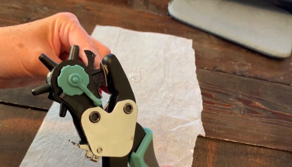 using a leather hole punch to put holes in the bat earrings diy project