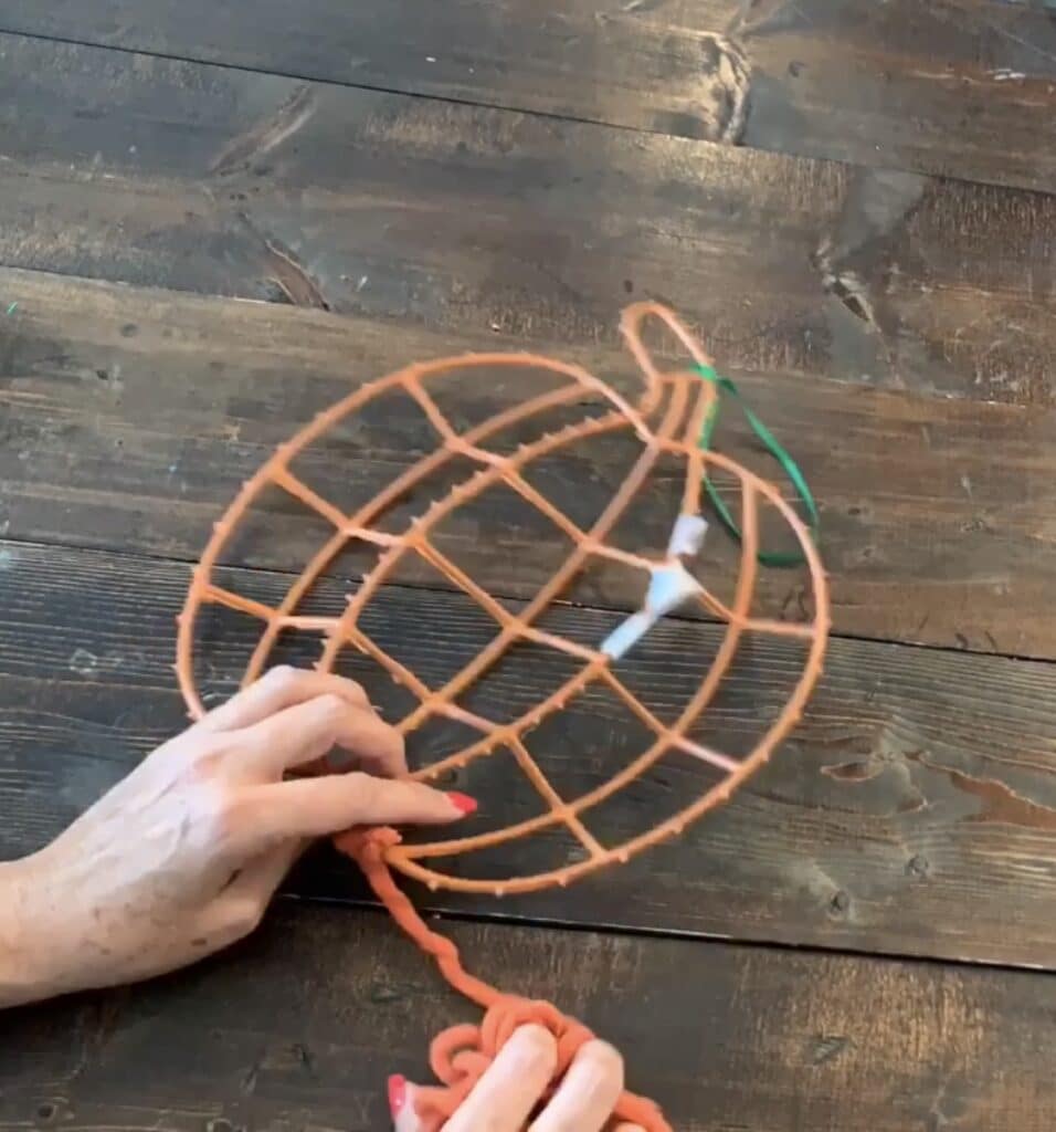 wrapping yarn around the dollar tree tinsel pumpkin frame
