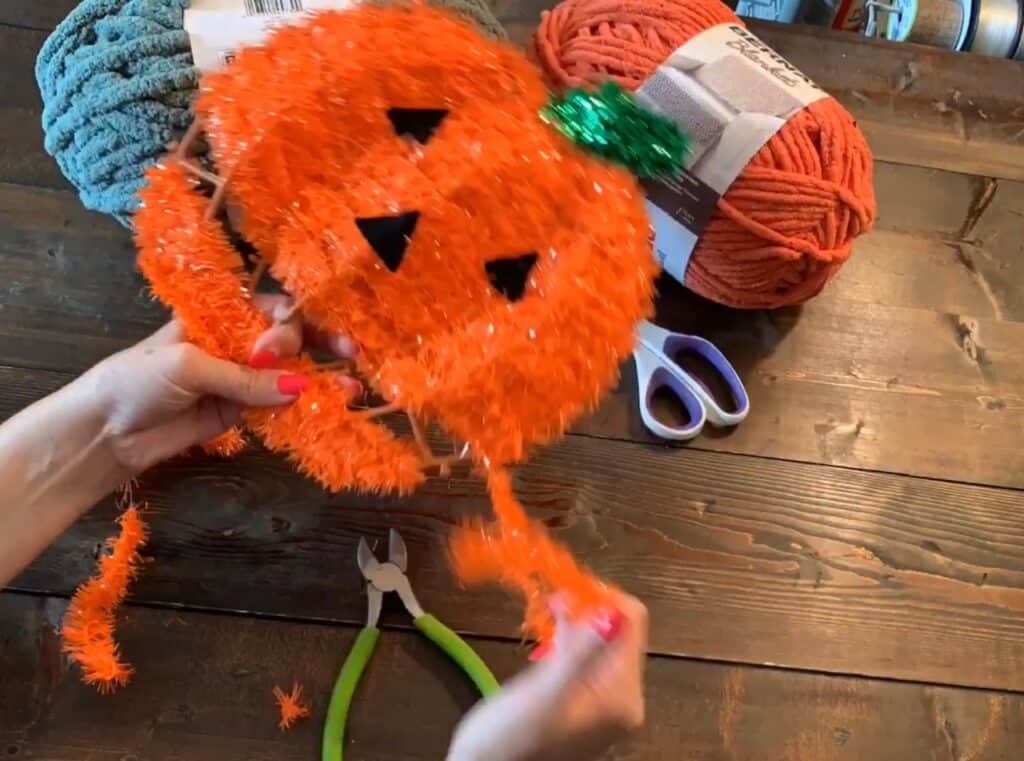 cutting off the tinsel from the Dollar tree wreath with wire cutters