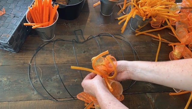 tying mesh bundles onto dollar tree pumpkin wreath form