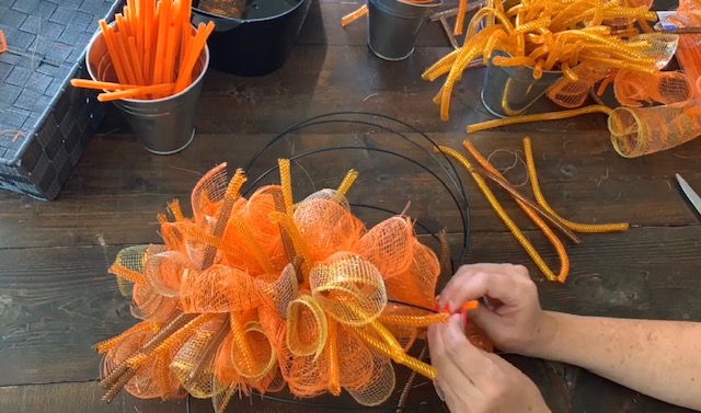 tying mesh bundles onto dollar tree pumpkin wreath form