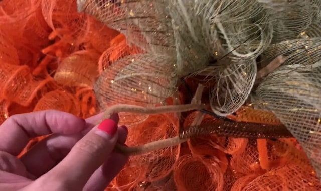 a pipe cleaner tied to back of wreath to hang the pumpkin mesh wreath