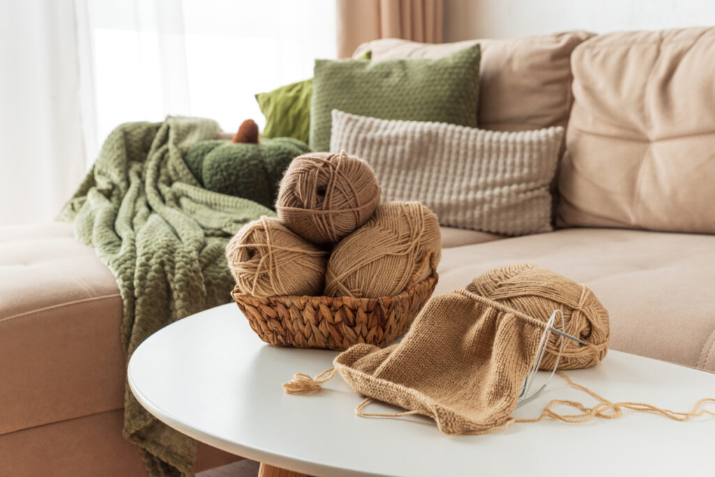 Knitting Basket with Yarn and Needles on White Table in Cozy Interior