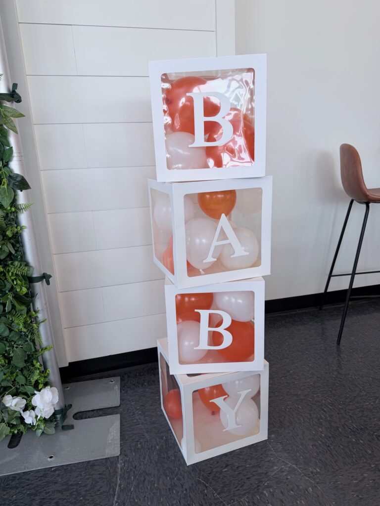 Clear decorative blocks filled with balloons, arranged as themed baby shower décor to add height and dimension.