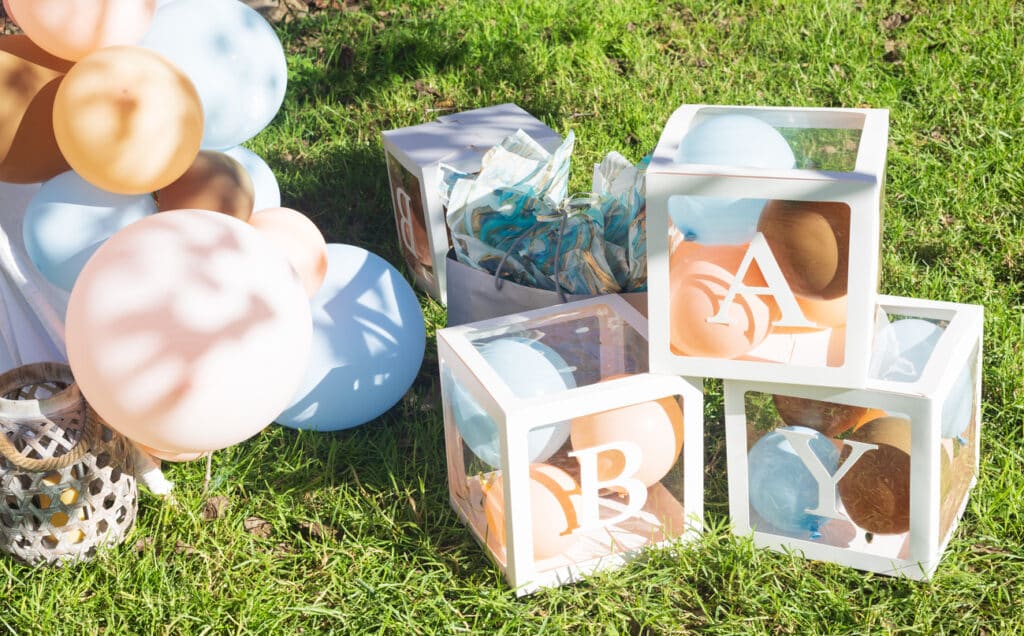 Outdoor baby shower setup with pastel balloons, clear boxes spelling “BABY,” and themed decorations, illustrating how to plan a baby shower with simple décor ideas.
