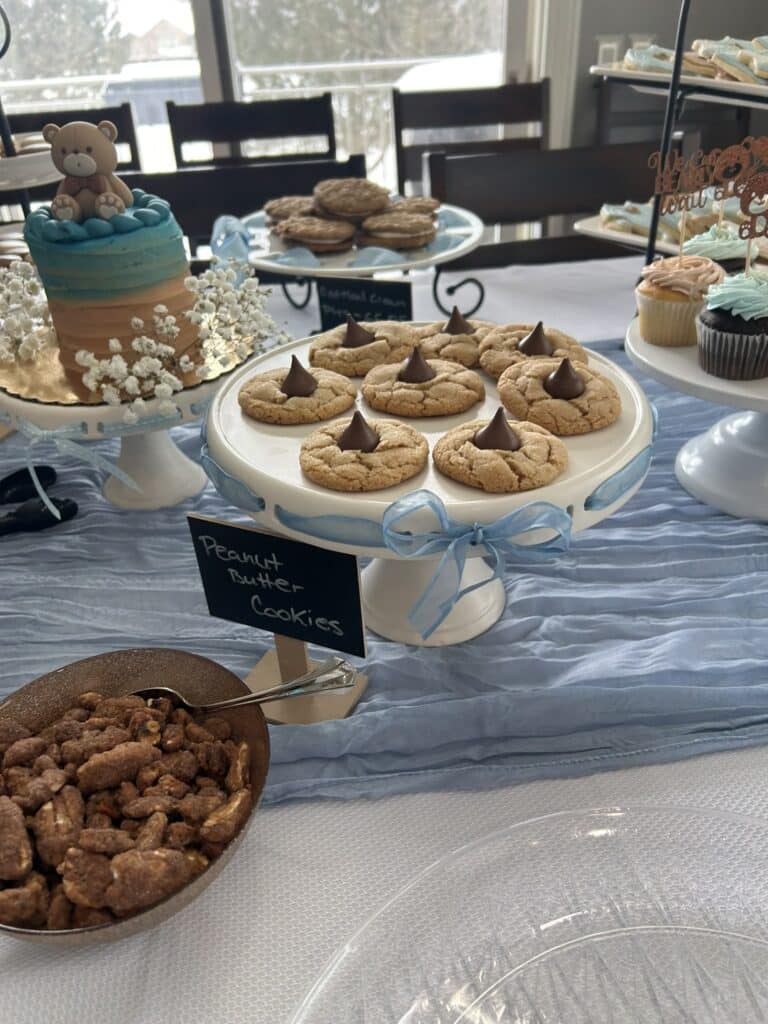 Bear‑themed baby shower dessert table with a small cake, cupcakes, cookies, and sweet treats, illustrating how to plan a baby shower with simple food ideas.