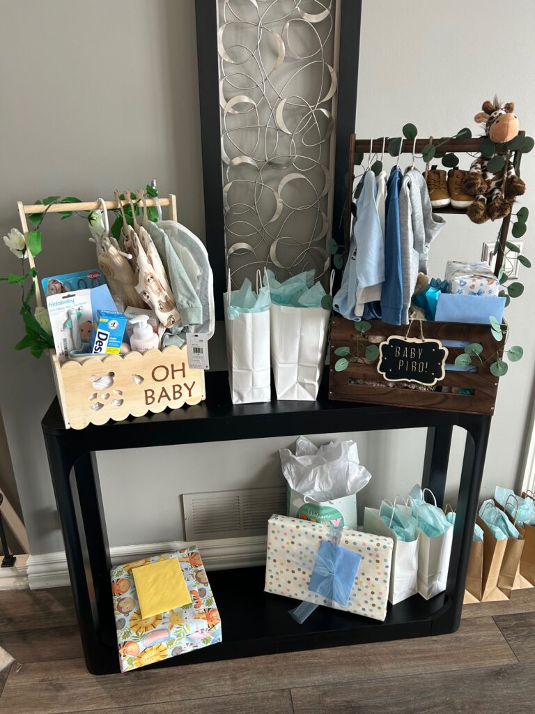 A baby shower gift display featuring a couple of mini clothing racks filled with baby outfits and themed gifts for a We Can Bearly Wait baby shower.