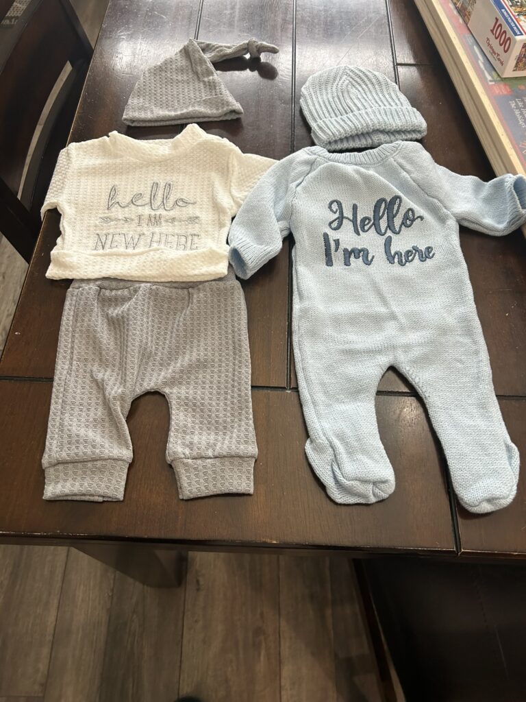 Two baby outfits laid out for a We Can Bearly Wait baby shower, chosen to match the theme and used as both décor and gifts.