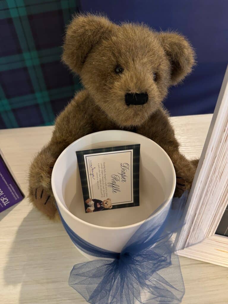 stuffed toy bear holding a bowl being used to collect the diaper raffle tickets