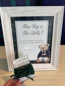pre-trimmed yarn tied onto a card next to sign that says "How Big is Her Belly", a baby shower game