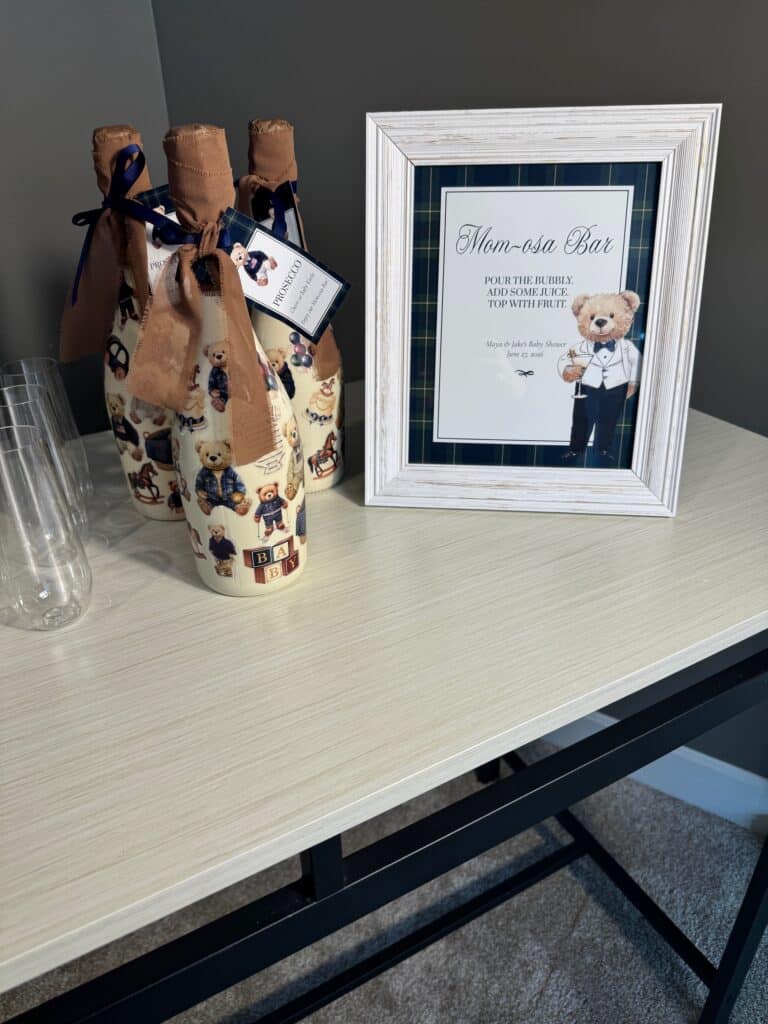 Finished teddy‑bear‑themed Prosecco bottles displayed beside a framed Mom‑osa Bar sign with cups ready for guests.
