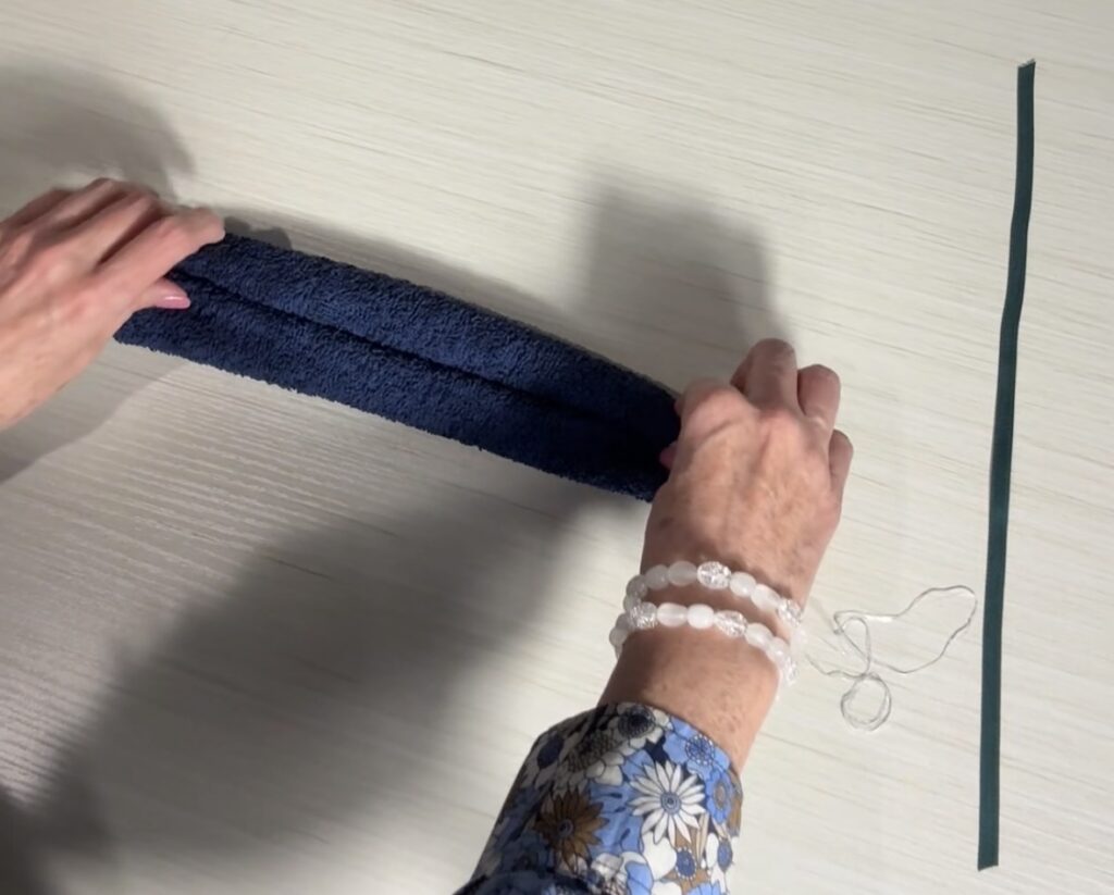 Washcloth with both sides rolled toward the center to begin forming the bear shape.