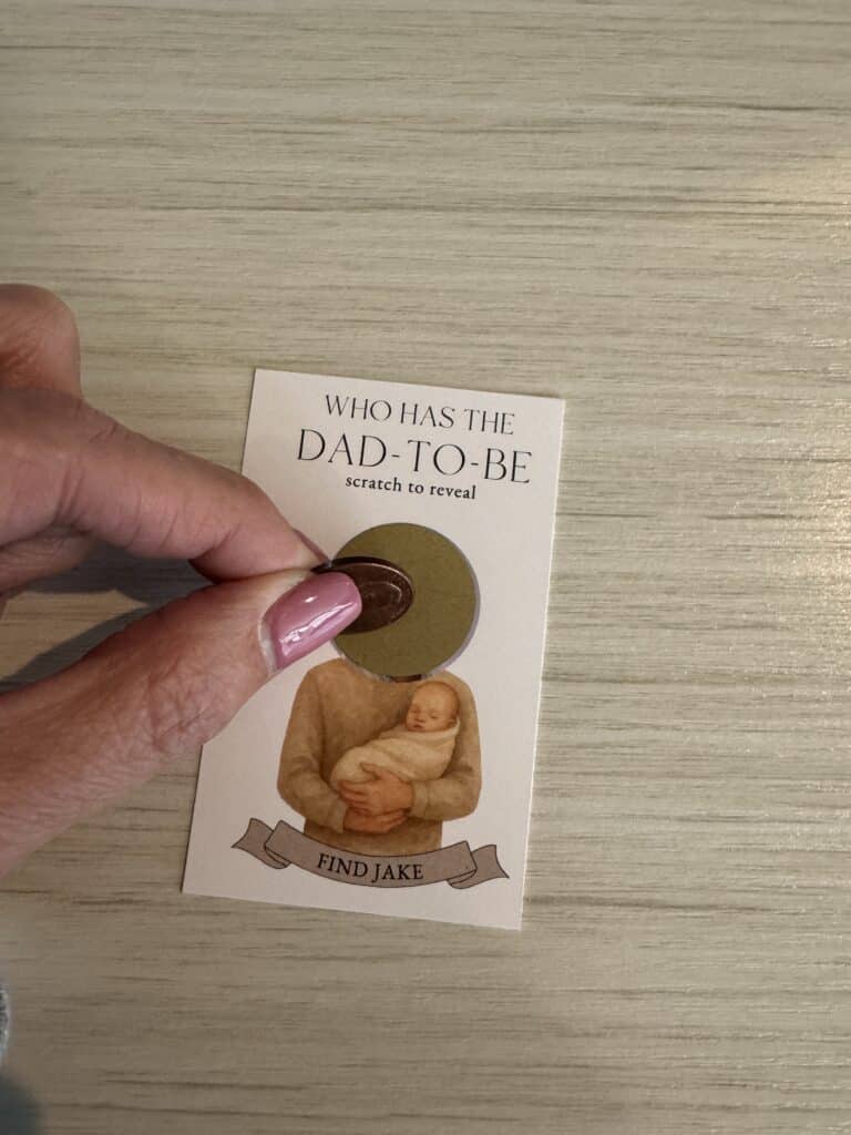 hand scratching off a Who has the dad-to-be baby shower game card